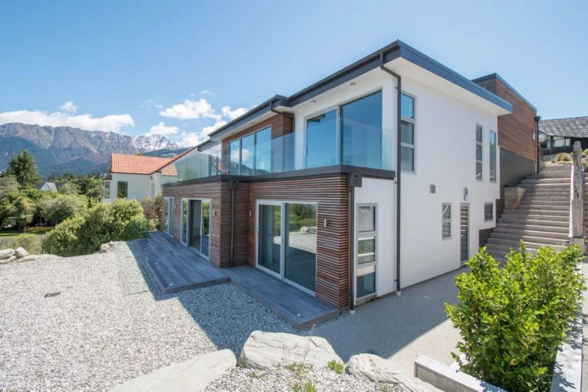 Eco-Panels residential project with a white exterior, wood cladding, and a lakefront mountain setting