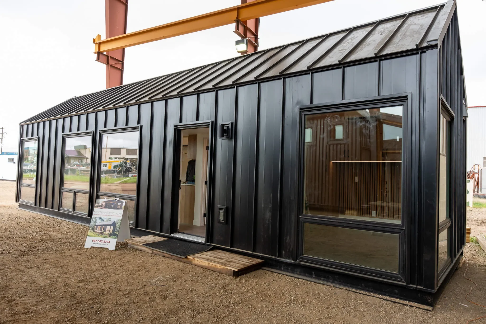 Completed Modern Modular Mod Two home with dark metal cladding, large windows, and a standing-seam roof.