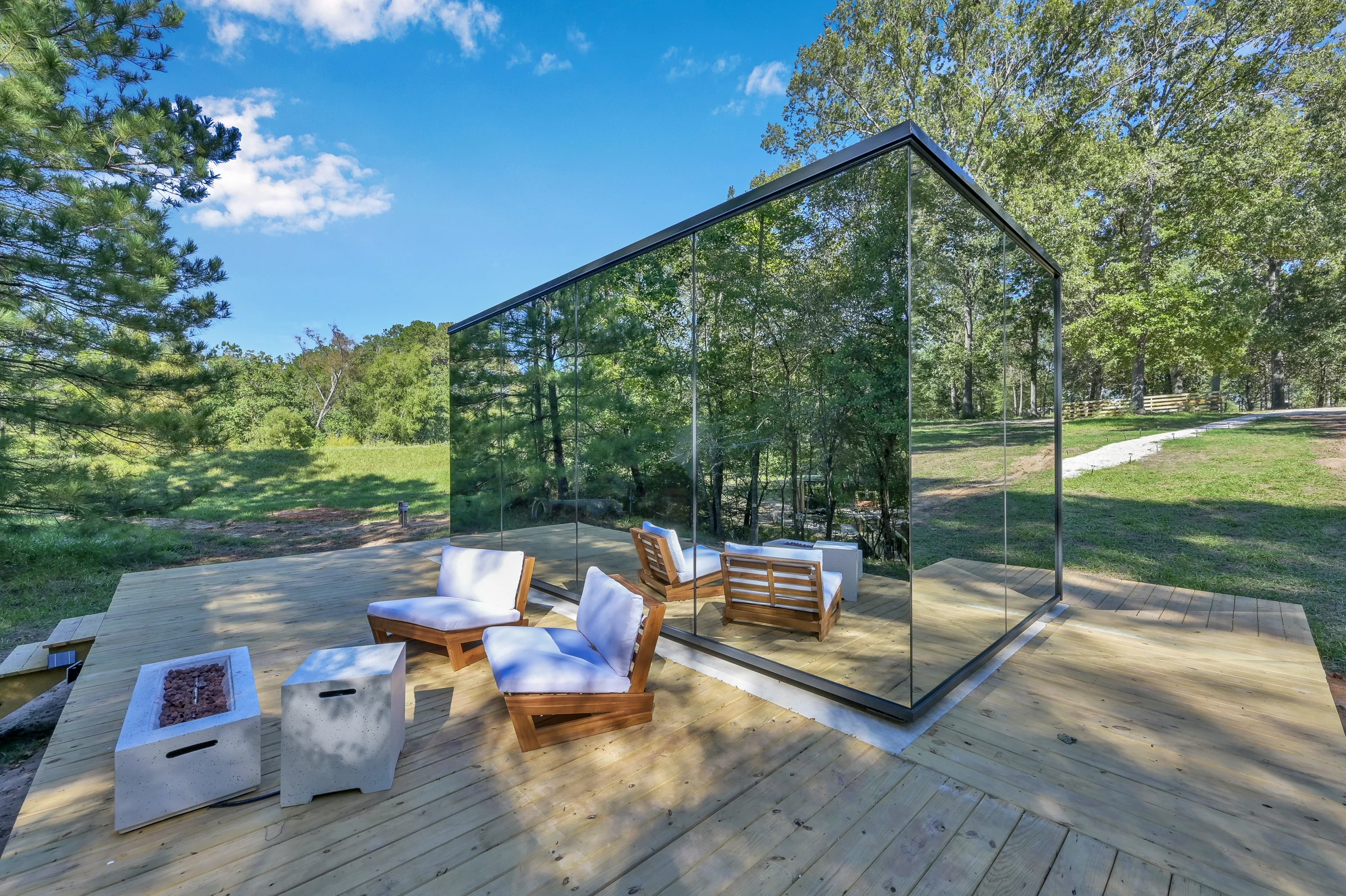 ÖÖD Signature House with mirror-glass walls on a timber deck in a wooded setting