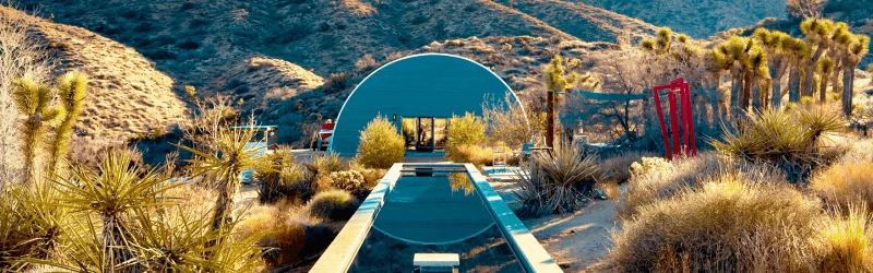 Turquoise arch pavilion beside a swimming pool in the Yucca Valley desert.