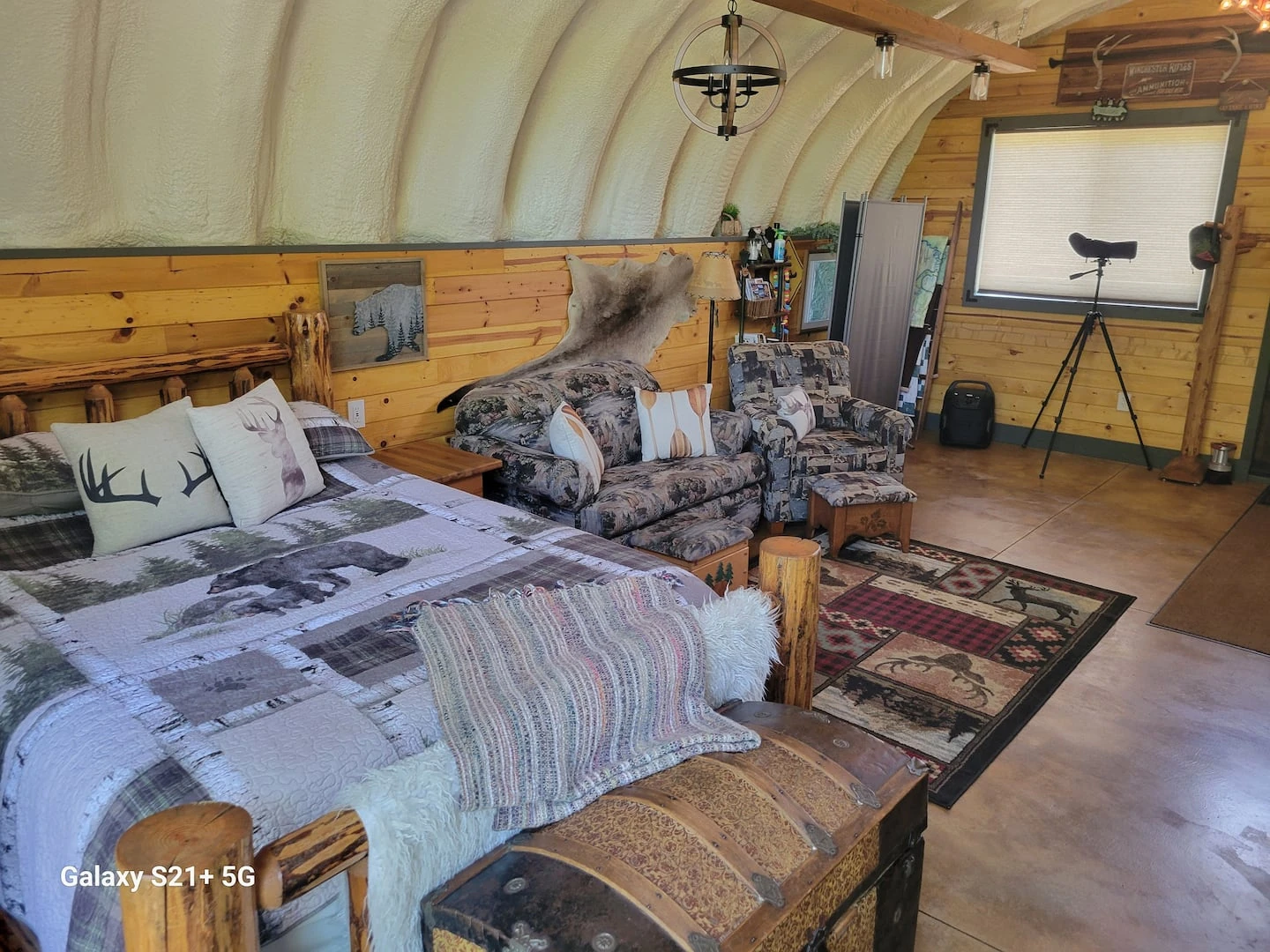 Bedroom inside a Quonset cabin with a curved wood finished ceiling.