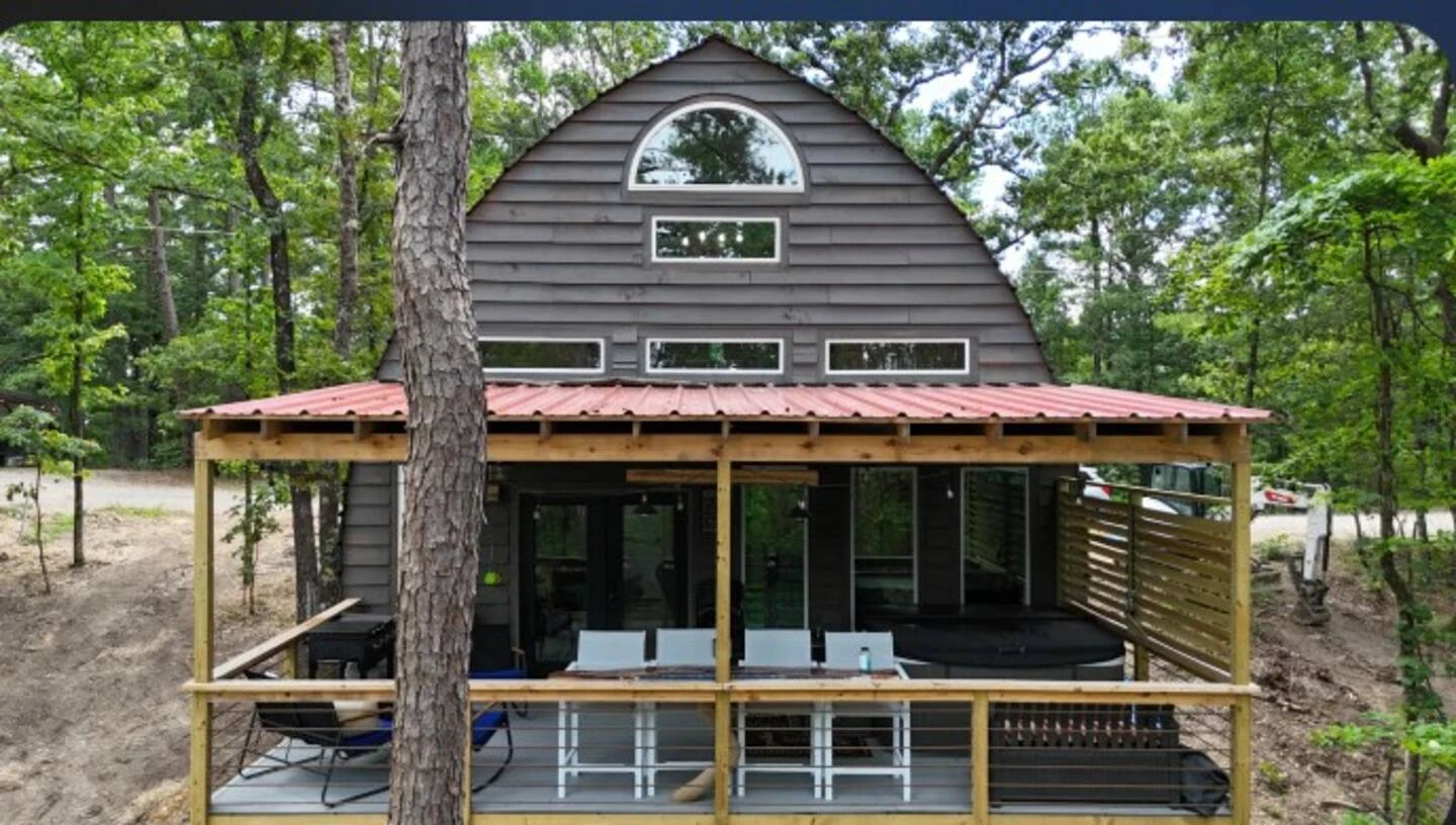 Pointed arch cabin with a dark end wall, large windows and a timber deck.
